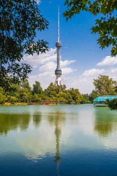 tall television tower in Tashkent in Uzbekistan against the background of a blue sky with a reflection in the pond water