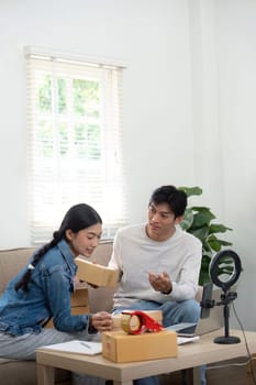 The young couple is engaged in an animated discussion about their business, sharing insights and plans as they sort through boxes in their cozy workspace.