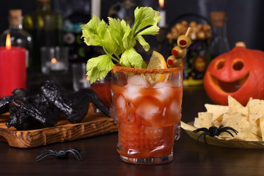 Michelada Cocktail, Bloody Mary. Mexican drink with tomato juice, lime juice, sauce and beer, garnished with celery stalk, lemon, olives. Halloween party ideas. 
