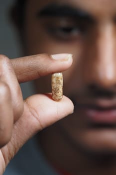 A person examines a small capsule with interest while focusing on details.