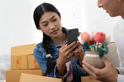 A couple is excitedly unpacking products in their living room, taking photos for social media as part of their entrepreneurial journey together.