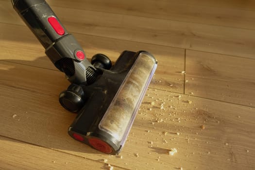 A vacuum cleaner is being used to clean crumbs on a hardwood floor.