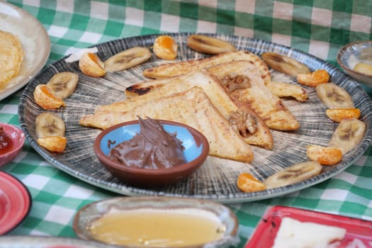 A delectable selection of French toast served with fruits and chocolate.