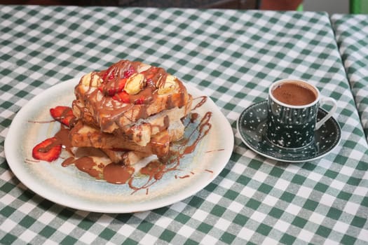 Delightful French toast served with chocolate and fresh fruit on a table.