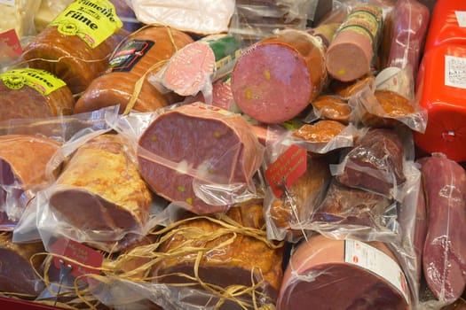 Various types of packaged deli meats are arranged attractively at a market.