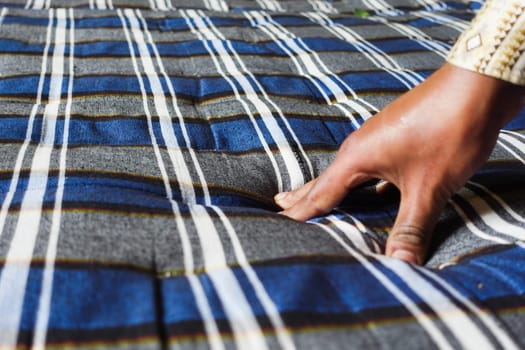 Person presses a blue and gray striped fabric to form a textured surface.