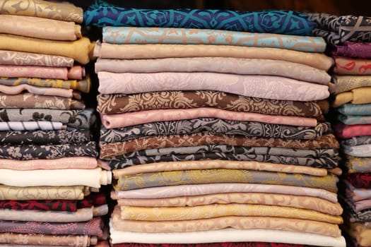 A colorful stack of assorted fabrics fills the shelves in a shop.