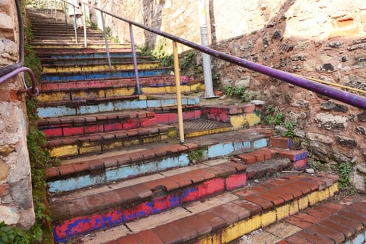 A colorful staircase with painted steps showcases artistry in an old area.