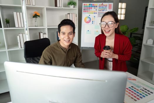 A dynamic duo of designers smiles as they review their work on the computer, celebrating a moment of teamwork and creative success.