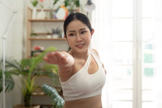 A woman performs a graceful arm extension in her yoga practice, showcasing empowerment and focus in her fitness journey.