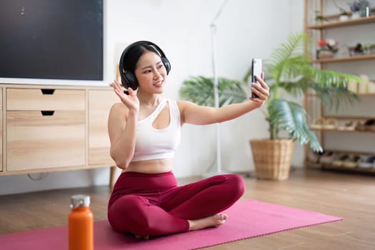 A woman connects with her online yoga community, practicing poses and engaging with friends through video chat.