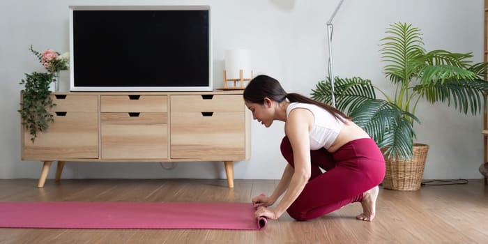 Emphasizing tranquility, a woman prepares to practice yoga by laying out her mat, creating a calm space for mindfulness and self-care.