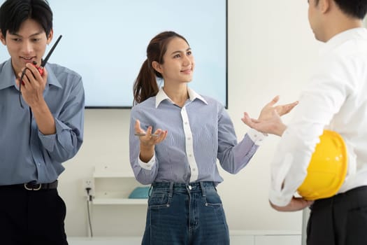 The team collaborates enthusiastically, using blueprints and digital tools for effective project planning. Their interactions highlight teamwork and innovation.