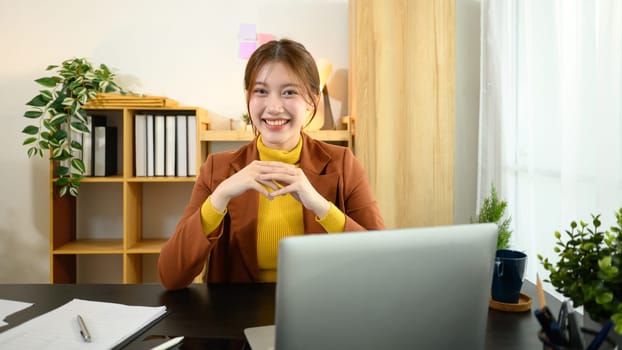 Portrait of happy young entrepreneur working with laptop at her desk.