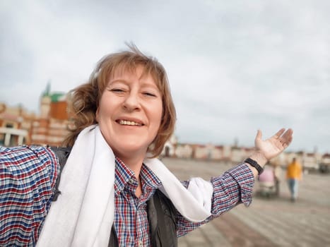 A middle-aged woman captures a joyful selfie while exploring a beautiful tourist destination during her travels.