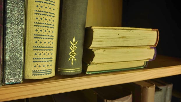 A view of two rows of very old books in the bookcase. Vintage books in an antique bookshelves. The concept of education, wisdom and love of knowledge. Close-up.