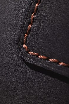 Close up showcasing brown stitching on black leather, highlighting craftsmanship and texture