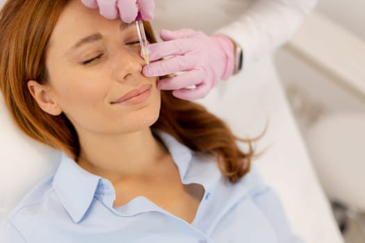 A woman enjoys a refreshing skincare procedure, lying comfortably as a skilled practitioner applies nourishing serum. The atmosphere is calming, promoting relaxation and wellness.