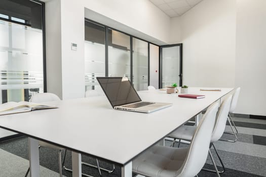 A modern laptop computer is placed on top of a white table, creating a simple and minimalist workspace in a bright room.
