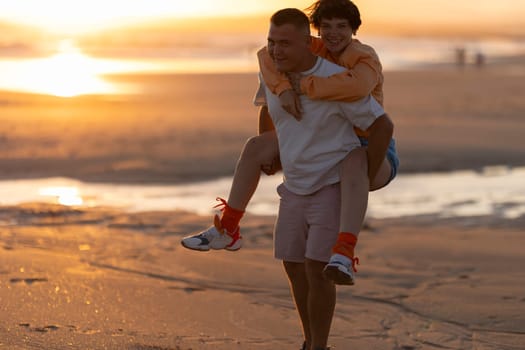 Man giving piggyback ride to woman on beach at sunset