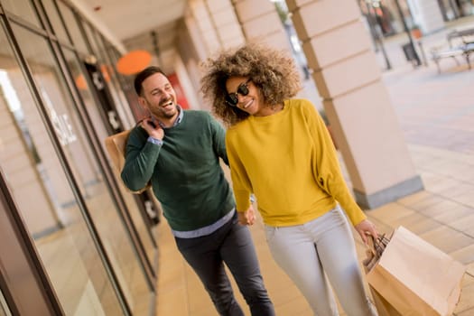 Beautiful young multiethnic couple with paper bags enjoying in shopping, having fun in the city