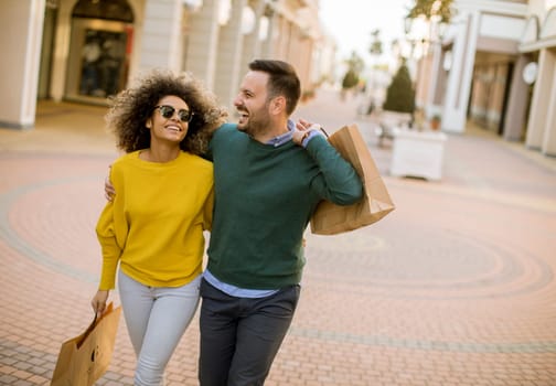Lovely young multiethnic couple with bags in the shopping