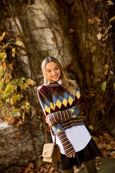 Pretty young woman standing outside at sunny autumn day