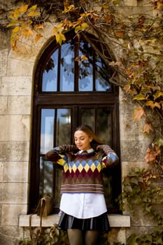 Pretty young woman standing outside at sunny autumn day