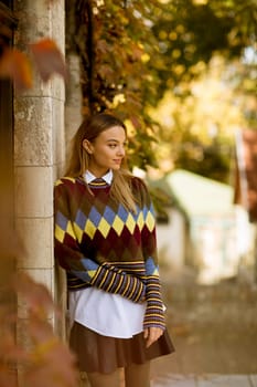 Pretty young woman standing outside at sunny autumn day
