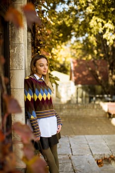 Pretty young woman standing outside at sunny autumn day