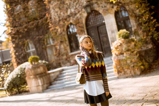 Pretty young woman standing outside at sunny autumn day