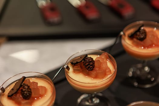 Elegant gourmet dessert served in delicate glassware, featuring a creamy panna cotta base topped with caramelized pear and thinly sliced black truffle