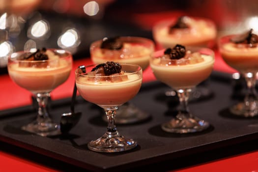 Elegant gourmet dessert served in delicate glassware, featuring a creamy panna cotta base topped with caramelized pear and thinly sliced black truffle