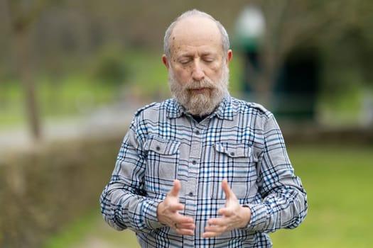Elderly man practicing mindfulness in a green park, enjoying the tranquility of nature and connecting with his inner self