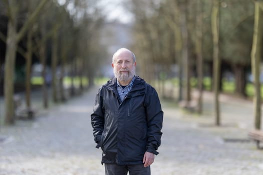Portrait of a confident senior man standing in a park, enjoying the fresh air and tranquility of nature