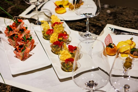 Elegant gourmet appetizer arrangement featuring salmon tartare cups, caviar bites, and luxury finger foods served in clear cups and plates, ideal for upscale events, weddings, and catering.