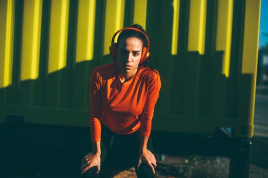 Attractive female runner taking break after jogging outdoors