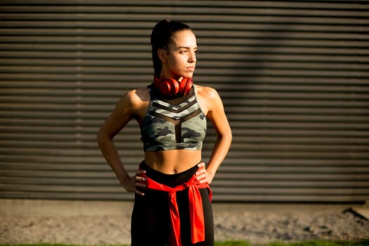 Pretty young woman takes a break after running in urban area
