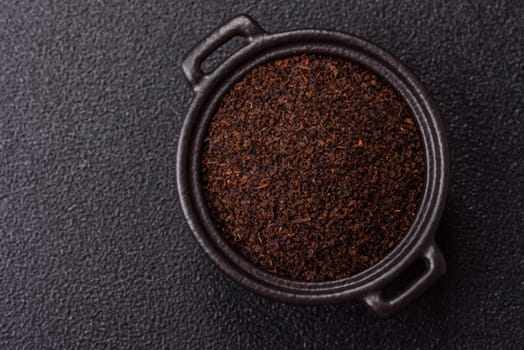Black tea dry crushed in bowl on dark concrete background