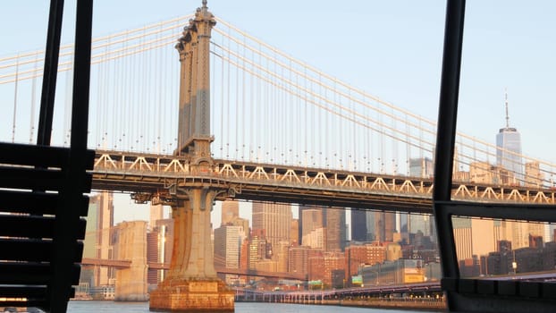New York City, United States - 7 Sept 2023: Manhattan Bridge to Brooklyn. Pier 35 swings bench, waterfront downtown skyline cityscape. World Trade Center skyscraper, financial district morning sunset.