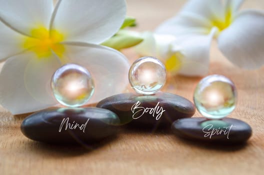 Mind, Body and Spirit text on black zen stones with shining marbles. Inner peace concept.