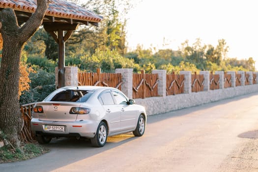 Silver car stands near a wooden fence on the road. Back view. High quality photo