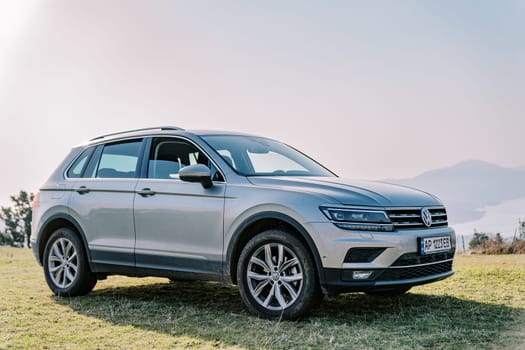 Silvery large Volkswagen car stands on a green meadow in the mountains. High quality photo