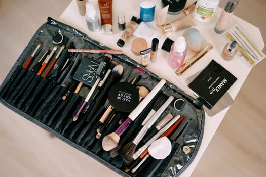 Set of makeup brushes lies on the table next to cosmetics. High quality photo