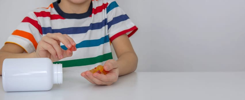 The boy eats jelly beans or takes vitamins.