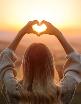 A woman creates a heart shape with their hands against a golden sunset, wearing a striped shirt while capturing the sun within the heart gesture. Generative AI