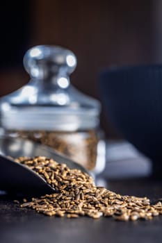 Milk thistle seeds in scoop on a black table.