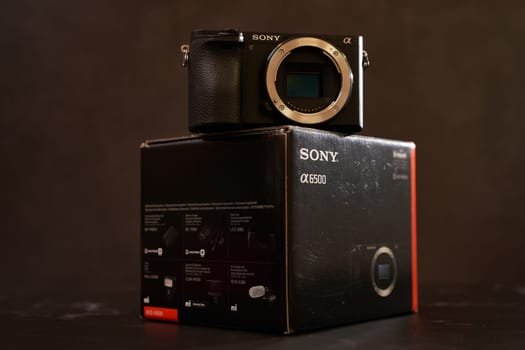 Sony A6500 mirrorless camera stands on its original packaging on a black table. High quality photo