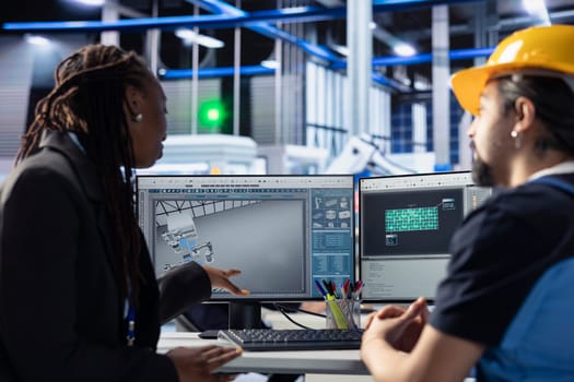Teamworking photovoltaics factory colleagues using tablet to do finetuning of system settings for maximum efficiency. Engineering team looking at solar panel assembly lines configuration on PC
