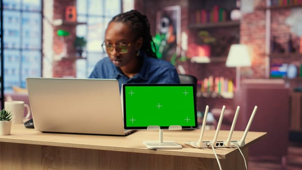 African American female freelancer browse troubleshooting guide next to copy space, working on debugging router issues to restore home network. Young woman struggles to solve tasks. Camera B.